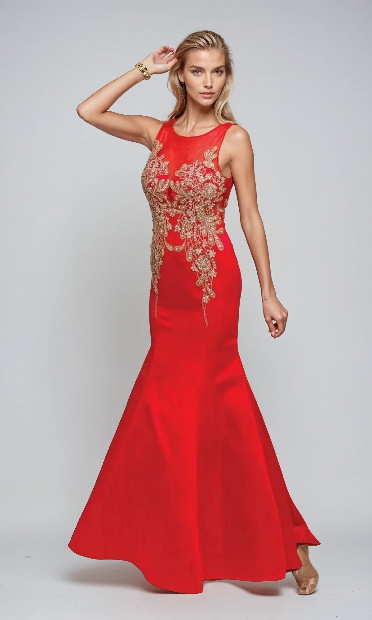 A woman poses against a plain light background wearing the Juliet 623 long prom dress, a sleeveless mermaid style with gold embroidery.